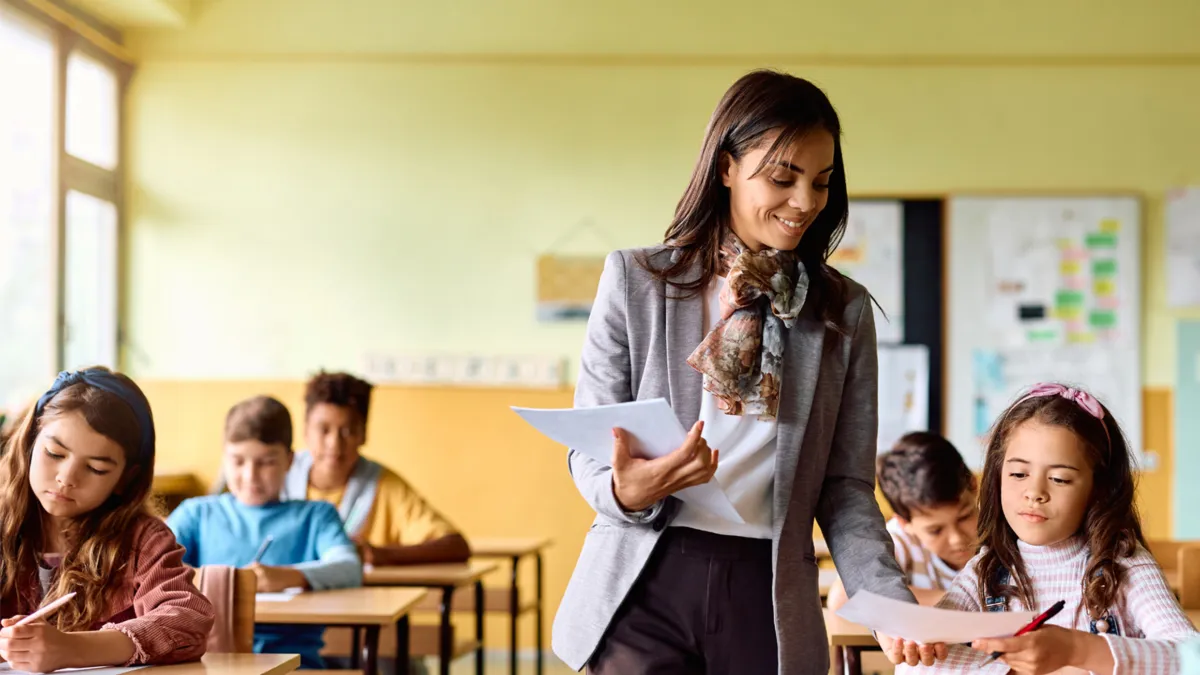 A teacher helping elementary students in class.