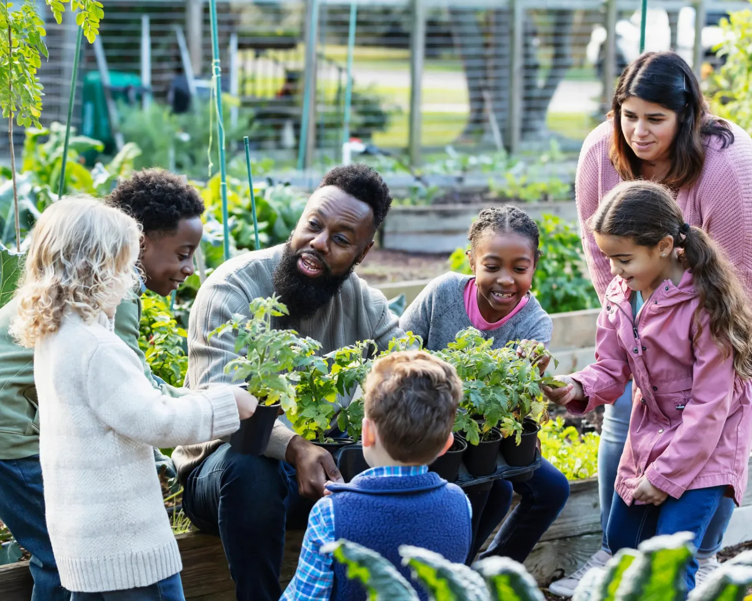 teachers and elementary students having a lesson in a school garden